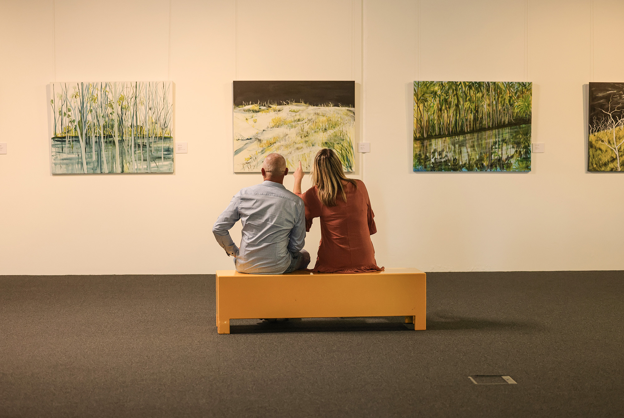 A couple admiring the artwork in the Nulla Nulla Gallery at the Slim Dusty Centre 